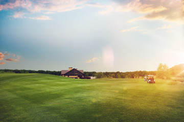 Golf cars on trimmed lawn, game course at sunset