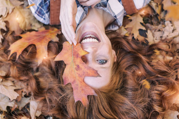 young red hair beauty lying in orange autumn leafes