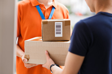 A person wearing an orange T-shirt and a name tag is delivering parcels to a client. Friendly...