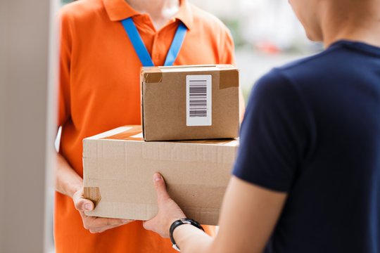 A person wearing an orange T-shirt and a name tag is delivering parcels to a client. Friendly worker, high quality delivery service.