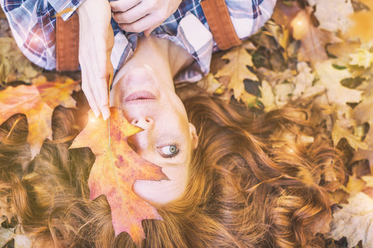 red hair beauty lying in autumn leaf