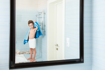 adorable healthy small child dry off his body with blue towel in morning bathroom