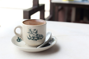 White coffee served in cup with saucer on white marble table