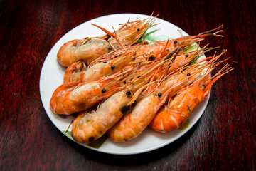 Grilled river shrimps on white plate on wooden background, Thai style food
