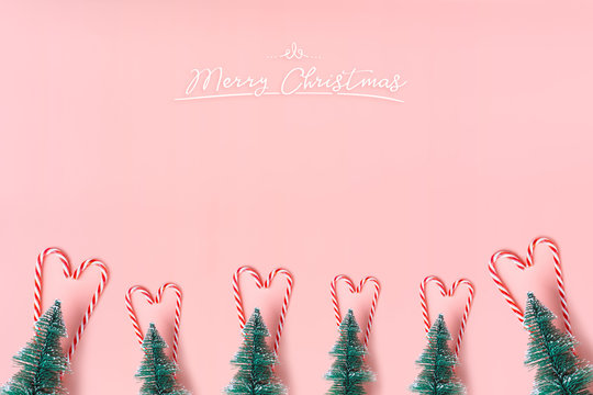 Tree Christmas tree with candy cane hanging on pastel pink wall with white Merry christmas word.Holiday festive celebration greeting card.