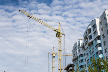 Crane and building under construction against blue cloudy sky.