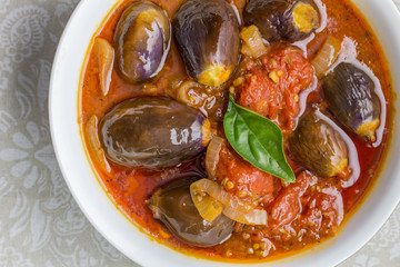 Baby aubergine casserole with basil, olive oil, onion and tomato - Close up top view photo