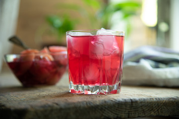 Red fruit drink with ice on a rustic background