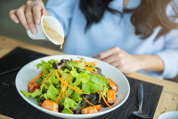 Happy woman eating healthy salad sitting on the table . Beautiful girl eating healthy food. Diet and healthy food concept