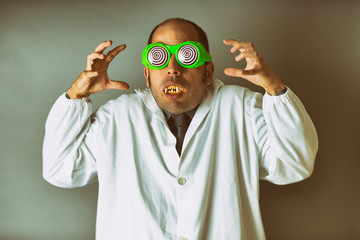 A man dressed as a mad scientist with a lab coat, crazy glasses, and vampire teeth