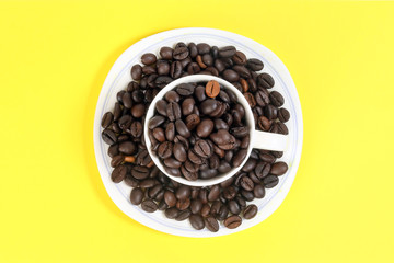 Coffee bean white ceramic cup saucer on yellow color background