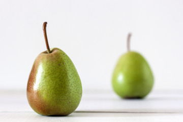 Fresh ripe pears lie on a white wooden table