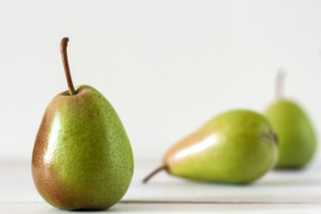 Fresh ripe pears lie on a white wooden table