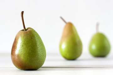 Fresh ripe pears lie on a white wooden table