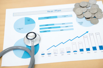 Stack of money coins with stethoscope checking