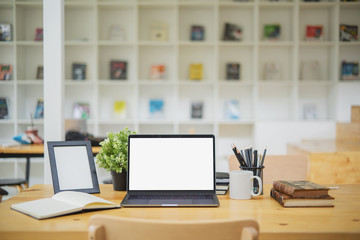 Mockup blank screen laptop on wood table in co-working space.