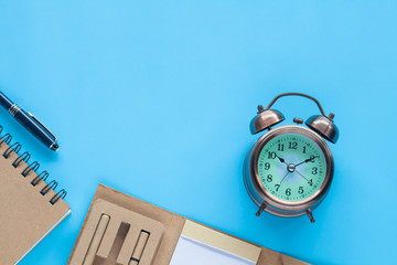 Alarm Clock and note book on color background.