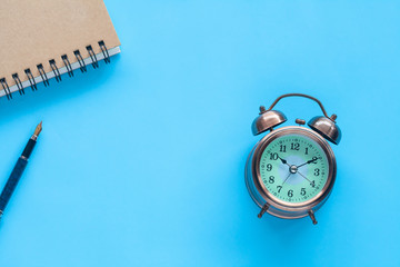 Alarm Clock and note book on color background.