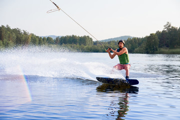 Fototapeta premium Young man riding wakeboard on a lake