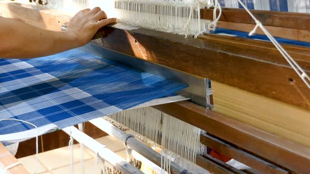 Close up woman is weaving Thai silk fabric by traditional weave machine in textile industry. (4K Video)