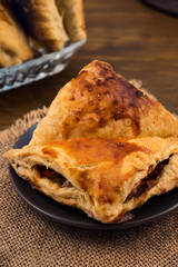 Puff pastry with Apple filling close-up, vertical frame on wooden background.
