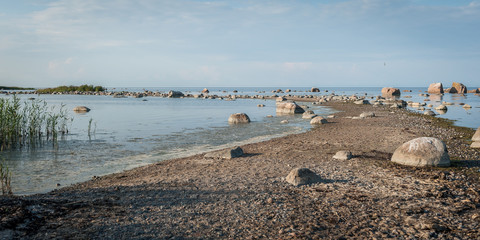 Long and thin peninsula with stones and boulders. The Gulf of Finland shore near Kasmu village in northern Estonia. Sunny. Copy space. Panoramic view.