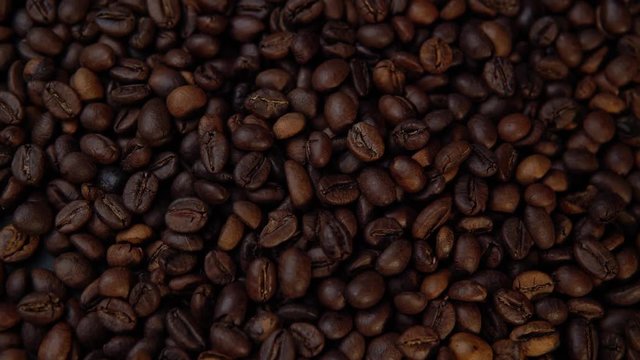 Dark roasted beans rotate counter-clockwise, top view of the coffee background.