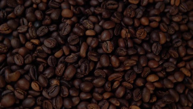 Dark roasted beans rotate counter-clockwise, top view of the coffee background.