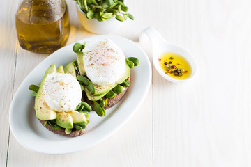 Avocado toast, cherry tomato on wooden background. Breakfast with toast avocado, vegetarian food, healthy diet concept. Healthy sandwich with avocado and poached eggs.