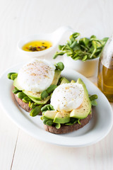 Avocado toast, cherry tomato on wooden background. Breakfast with toast avocado, vegetarian food, healthy diet concept. Healthy sandwich with avocado and poached eggs.