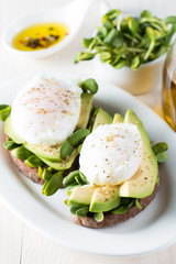 Avocado toast, cherry tomato on wooden background. Breakfast with toast avocado, vegetarian food, healthy diet concept. Healthy sandwich with avocado and poached eggs.