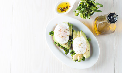Avocado toast, cherry tomato on wooden background. Breakfast with toast avocado, vegetarian food, healthy diet concept. Healthy sandwich with avocado and poached eggs.