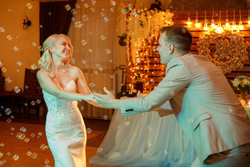 Wedding. First wedding dance of stunning bride and attractive groom, cheerfully smiling, bubbles....