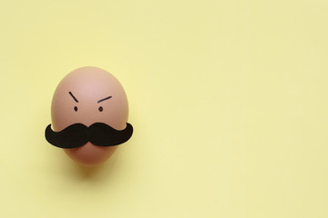 Egg with mustache on light yellow background for Movember concept which is an annual event involving the growing of moustaches during the month of November to raise awareness of men's health issues.