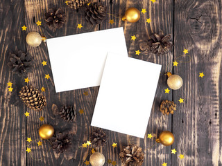 Branding mock-up two greeting cards. Christmas new year card mockup with fir cones, christmas golden balls and confetti stars on dark wooden background. Top view