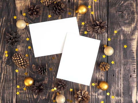 Branding mock-up two greeting cards. Christmas new year card mockup with fir cones, christmas golden balls and confetti stars on dark wooden background. Top view