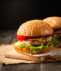 Close-up photo of home made hamburger with beer made of beef, onion, tomato, lettuce, cheese and spices. Fresh burger closeup on wooden rustic table with potato fries and chips.