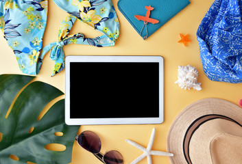 Woman's accessories for summer travel flay lay on bright yellow background with colorful bikini,...