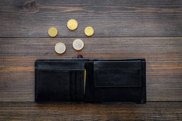 Unemployment concept. Lack of money. Coins fall out of wallet on dark wooden background top view