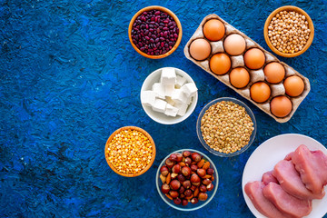 Food for sportsmen. Legumes, nuts, low-fat cheese, meet, eggs on blue background top view space for...