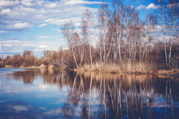 A beautiful autumn landscape, a pond in the forest, the trees are reflected in the water, an image with retro toning