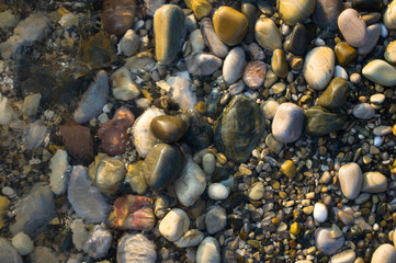 pebble stones on the sea beach, the rolling waves of the sea with foam