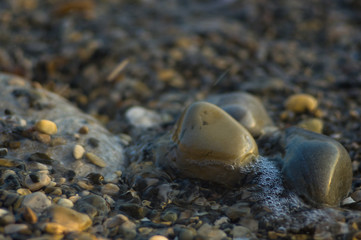 pebble stones on the sea beach, the rolling waves of the sea with foam