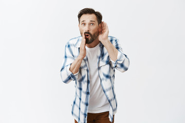 Do not tell anyone, listen. Portrait of charming talkative adult male bending towards camera,...