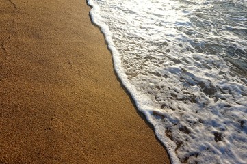 Waves of the sea rolling on yellow sand.