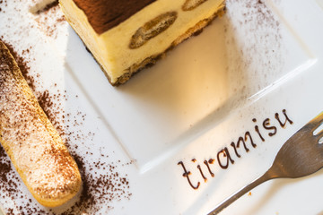 Tiramisu, traditional Italian dessert on a white plate.
