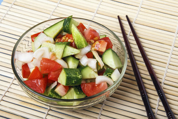 Fresh salad from organic natural vegetables and chopstick on bamboo mat. Chinese or japanese kitchen concept. Copy space