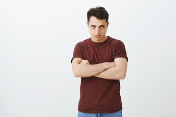Offended disappointed attractive guy in casual clothes, holding hands crossed on chest and looking...