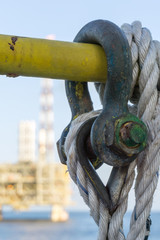 A green shackle secured on a handrail with a nylon rope on a construction barge at oilfiled