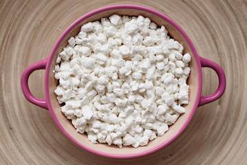 Cottage cheese in a ceramic bowl on a wooden bamboo stand background, homemade rural healthy food